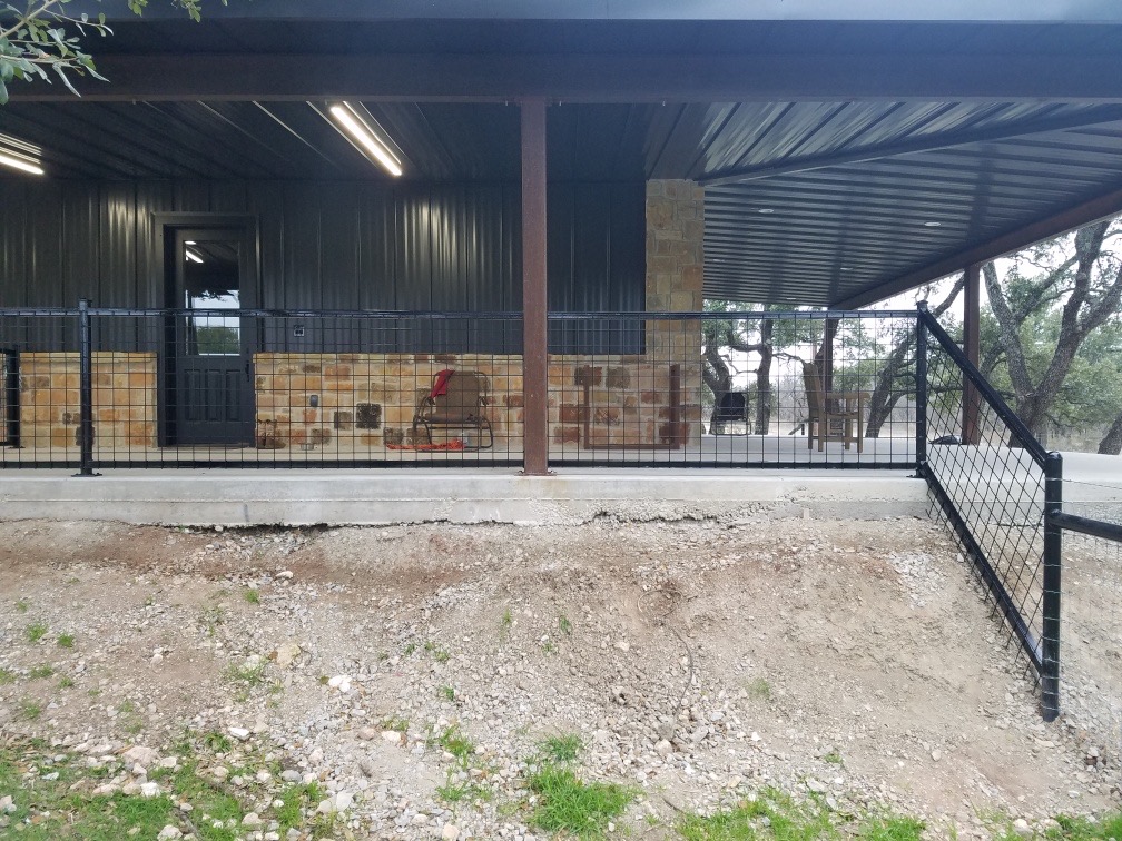 Metal barn with covered porch, stone accent wall, and welded wire railing — Brownwood TX
